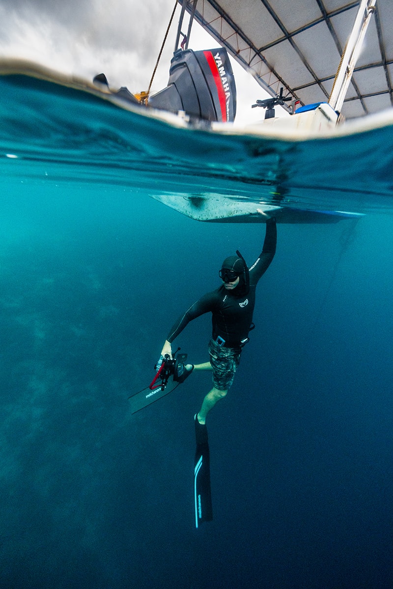 Man grabbing boat while under water.